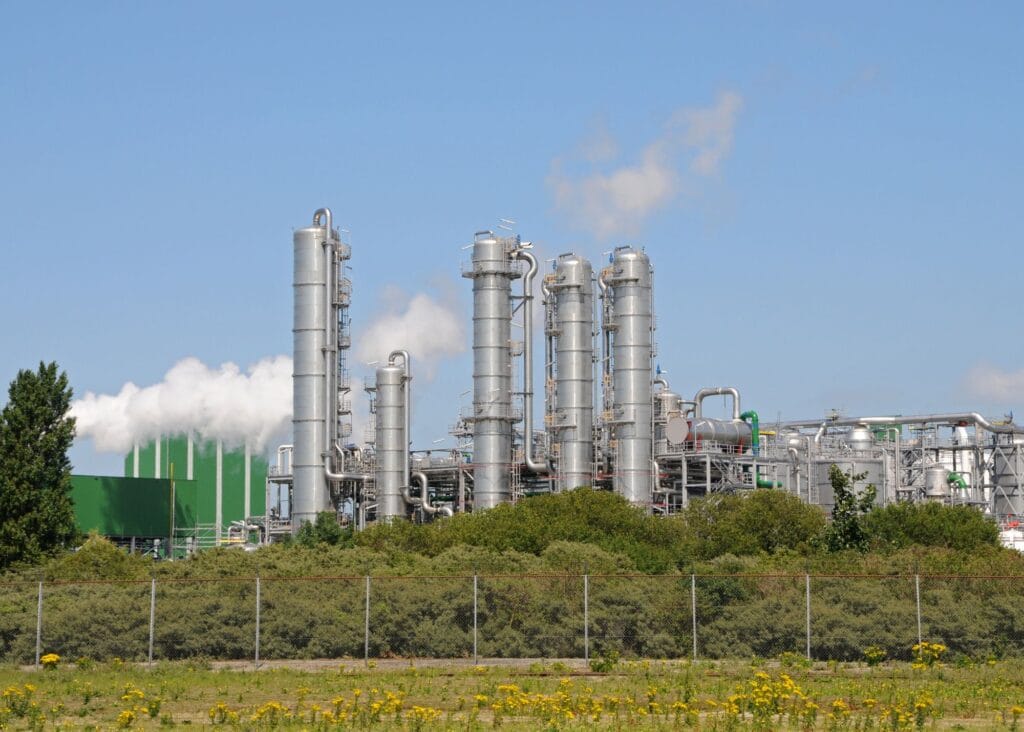 exterior shot of tall distillation towers with greenery in foreground